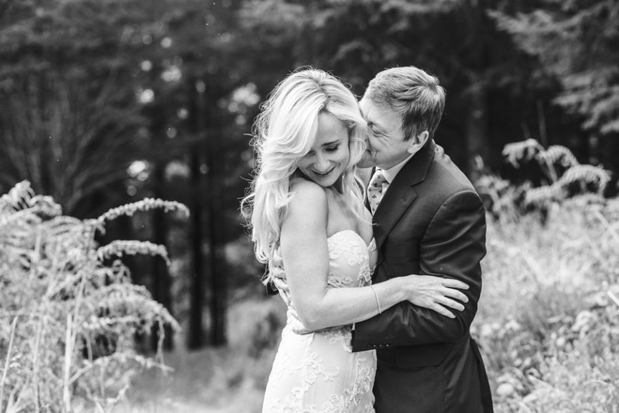 Bride and groom getting married in Scotland outside in woods with groom kissing brides cheek